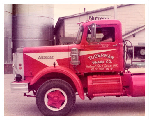 80's red semi-truck with with white wheels and red hub cap with "Toberman Grain Co." on the door drivers door